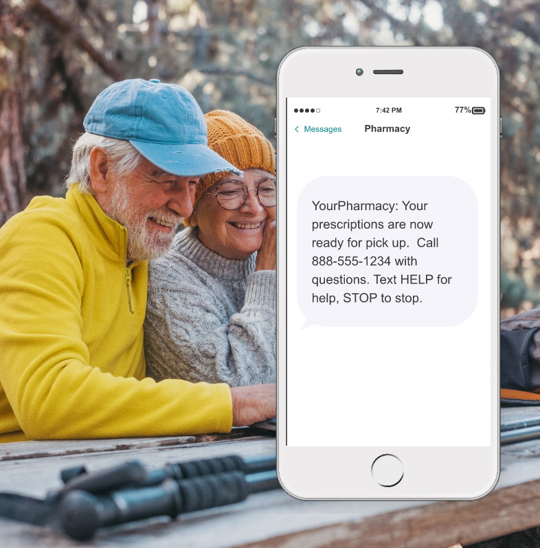 A senior couple smiles as they look at a laptop in the park