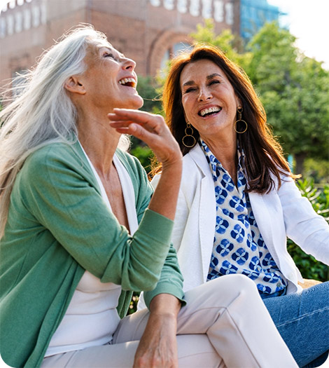 Two middle aged women smiling in park