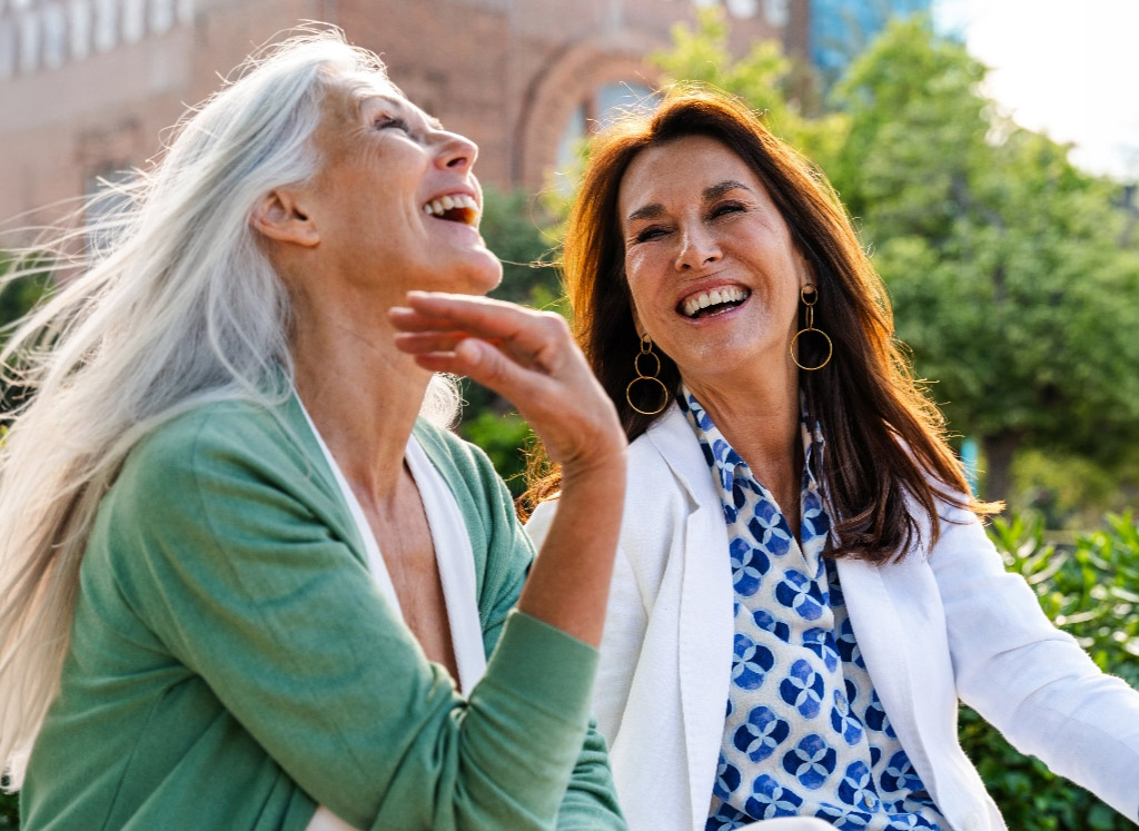 Two middle aged women smiling in park mobile
